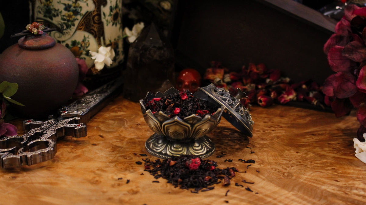 Decorative setting with a bowl of dried flowers, crosses, and a vase on a wooden surface.