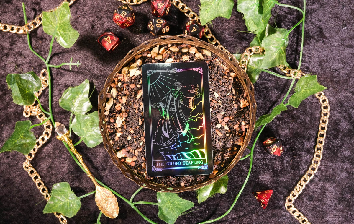 Decorative setting with a tarot card, gold chains, and green leaves on a dark background
