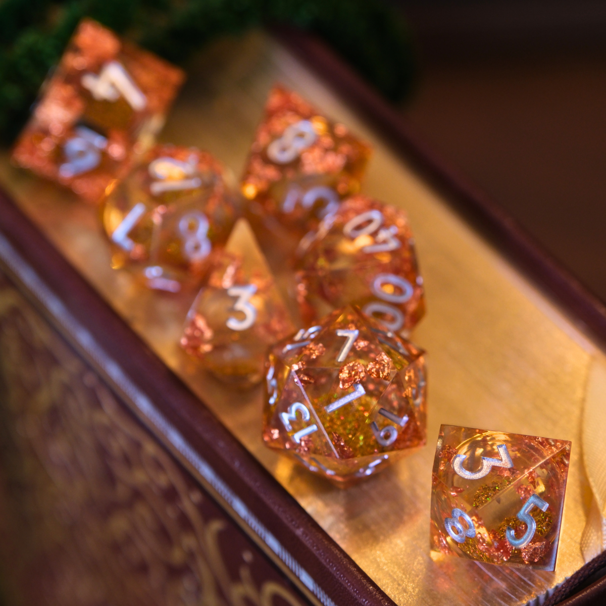 Set of orange polyhedral dice with white numbers on a reflective surface.