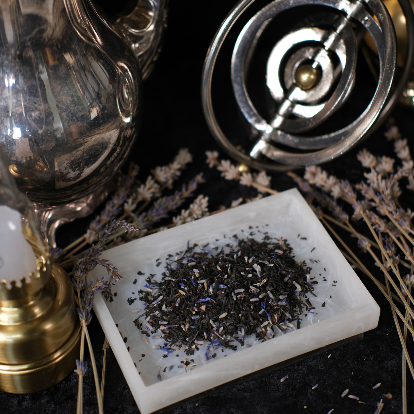 Tea leaves on a white stone surface with a vintage-style lamp and lavender flowers in the background.