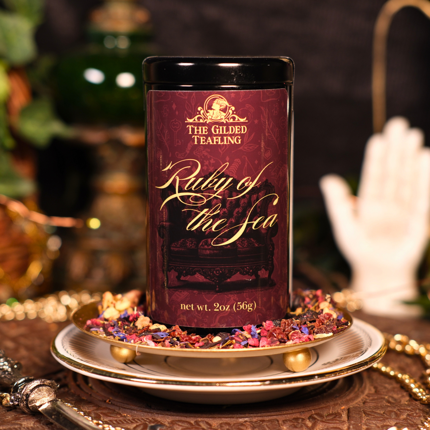 Tea canister labeled 'Ruly of the Sea' by The Gilded Teafling on a decorative plate with flowers.