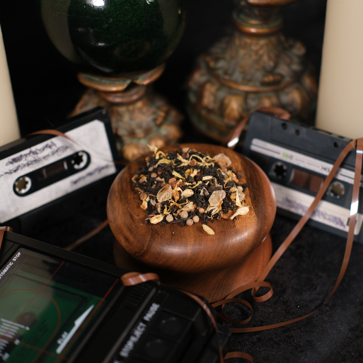 Wooden bowl with dried herbs surrounded by vintage audio cassettes and a radio.