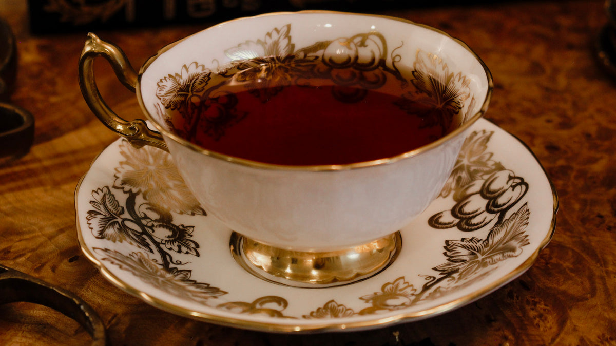 Dark brown liquid in a white and gold teacup